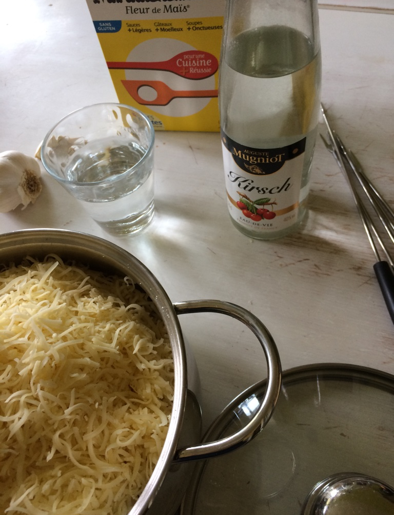 Casserole de fromage râpé et ingrédients pour préparation de la fondue savoyarde